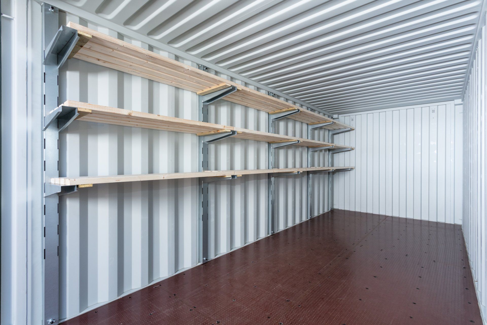 Empty cargo container interior with shelving on the wall.