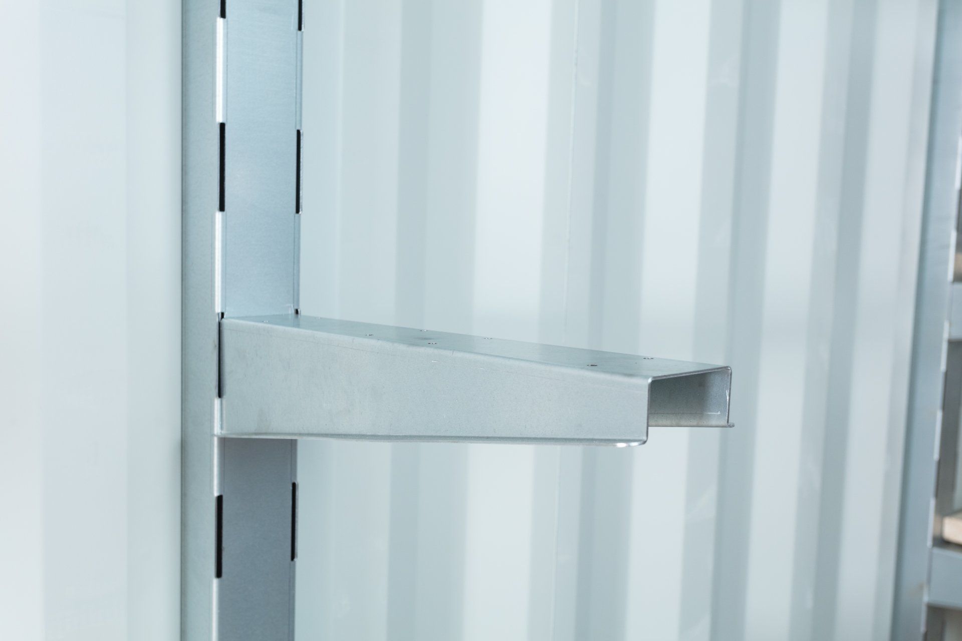 Metal shelf bracket attached to a white corrugated wall.
