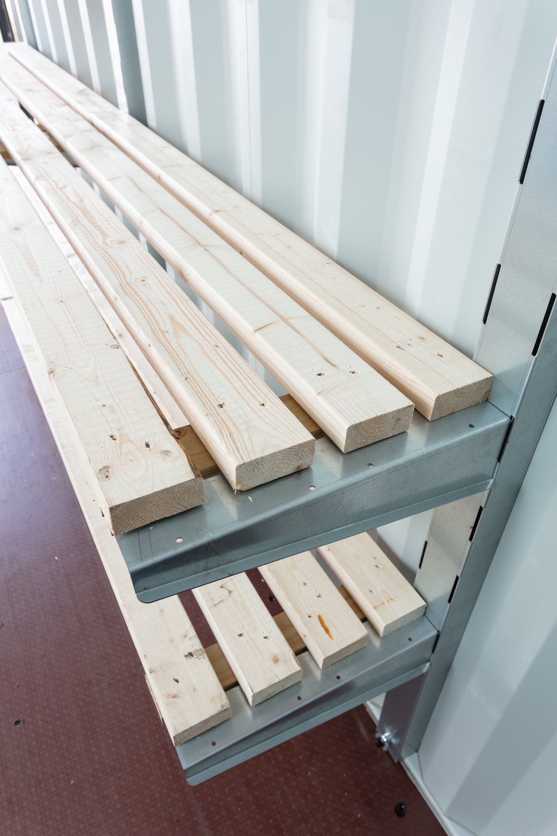 Wooden planks on metal shelving inside a white structure.
