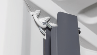 A metal bracket secures a gray vertical support to a white wall.