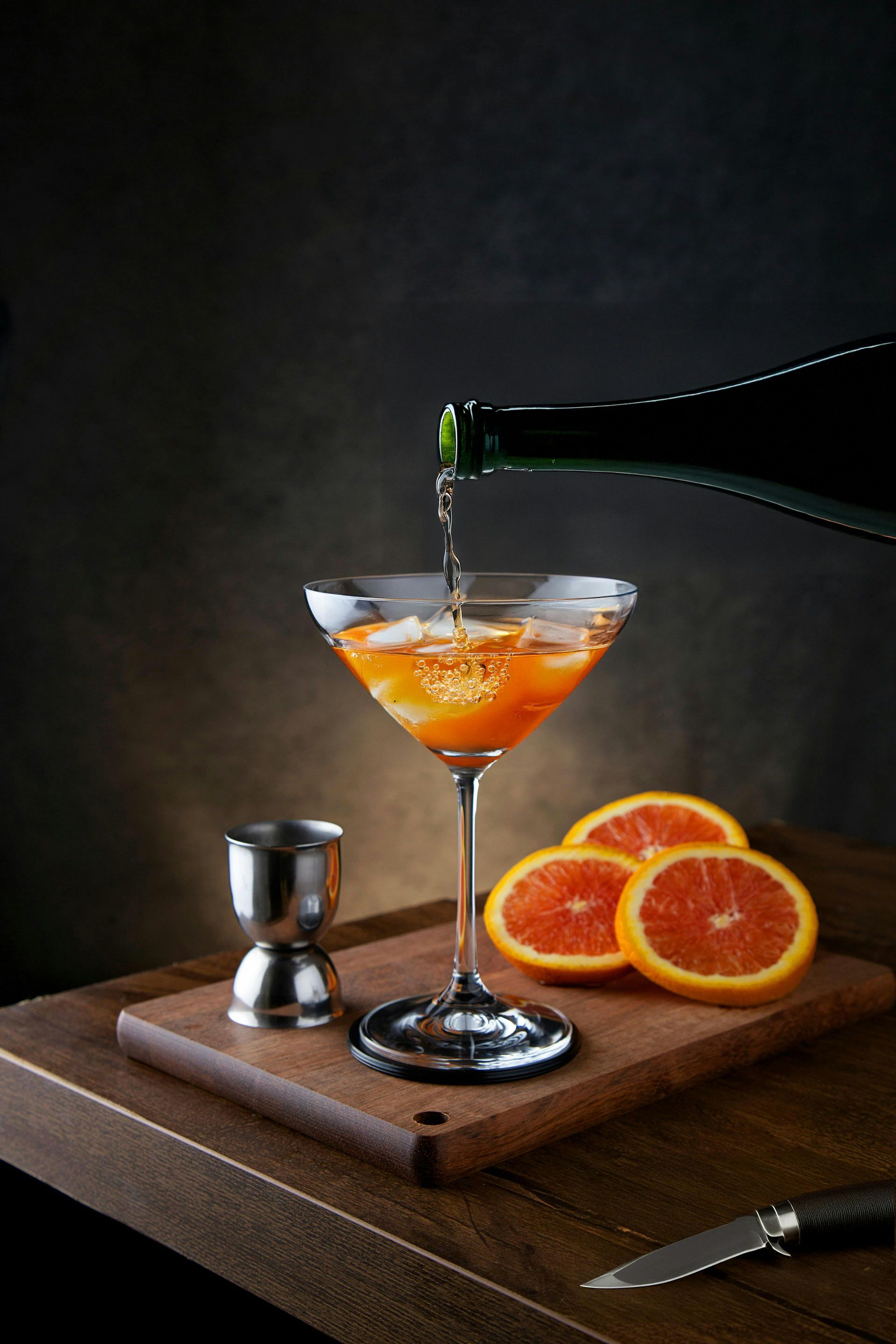 A martini is being poured into a glass on a wooden table.
