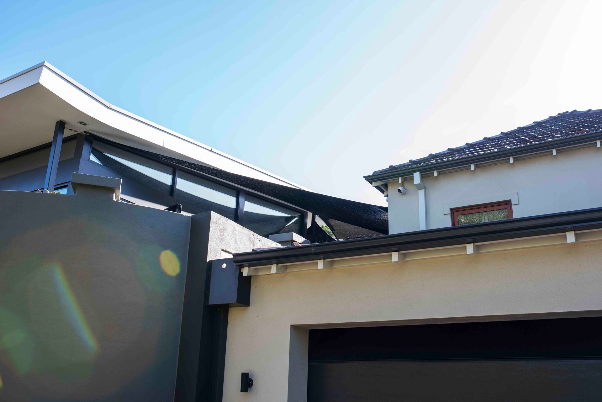 Exterior architectural detail showing two contemporary rooflines against a blue sky.