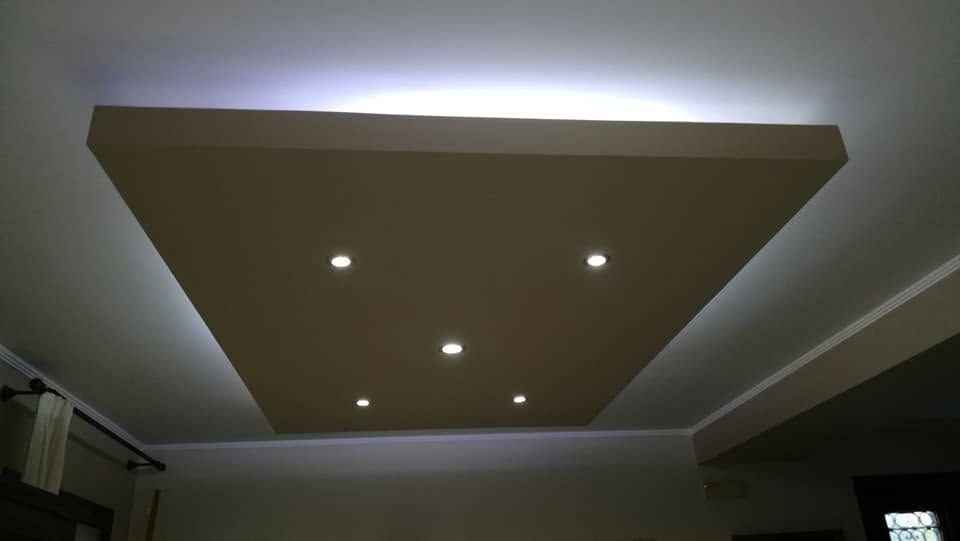 Soffitto con pannello marrone incassato e cinque piccole luci incassate in una stanza poco illuminata