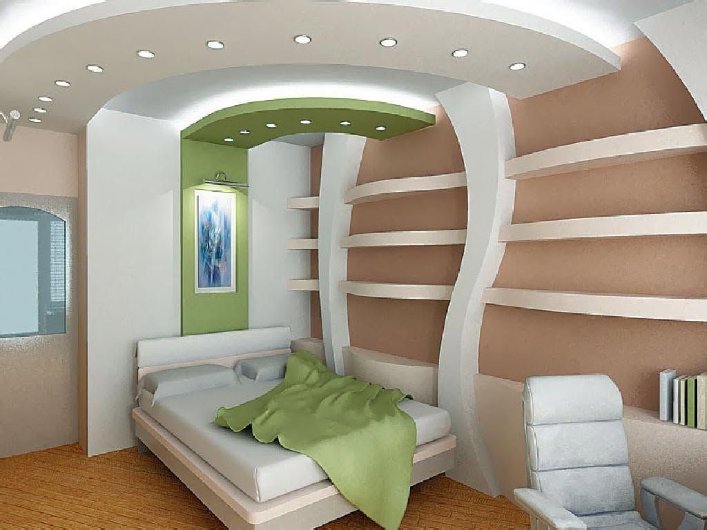 Camera da letto moderna con scaffali a muro, letto con coperta verde e faretti a incasso sul soffitto.