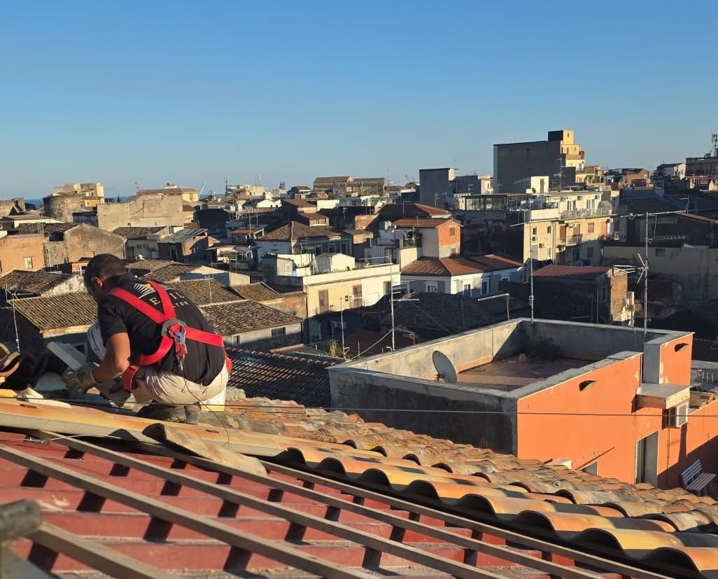 Un operaio specializzato che lavora su fune scende lungo la facciata di un edificio in mattoni, accanto a una finestra.