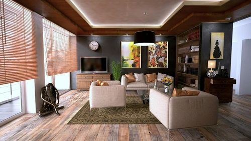 A modern living room with beige armchairs, a patterned rug, a television on a wooden unit, and artwork on a dark wall.