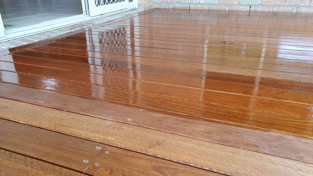 A Wooden Deck With a Reflection of a Window in It — Timbertop Floor Sanding & Polishing In Normanton, QLD