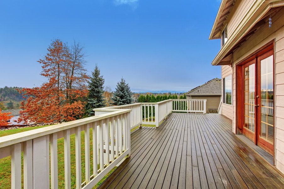 A Large Wooden Deck With a White Railing and Sliding Glass Doors — Timbertop Floor Sanding & Polishing In Cairns, QLD