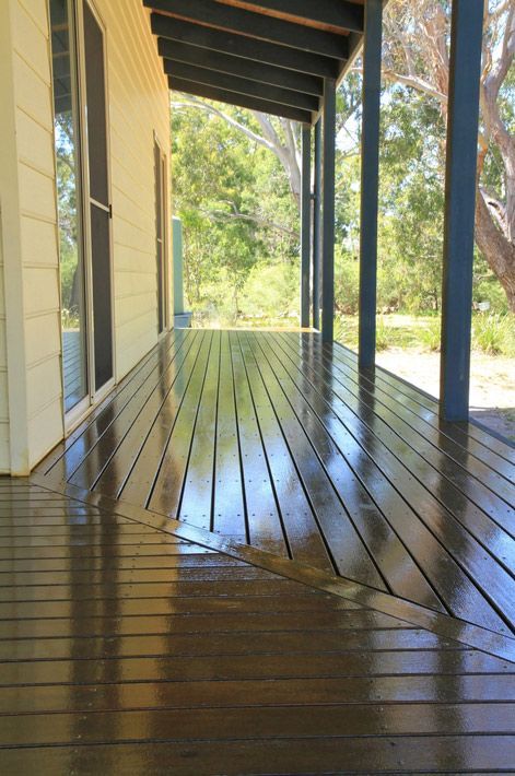 A Wooden Deck With a Covered Porch and Trees in the Background — Timbertop Floor Sanding & Polishing In Cassowary Coast, QLD