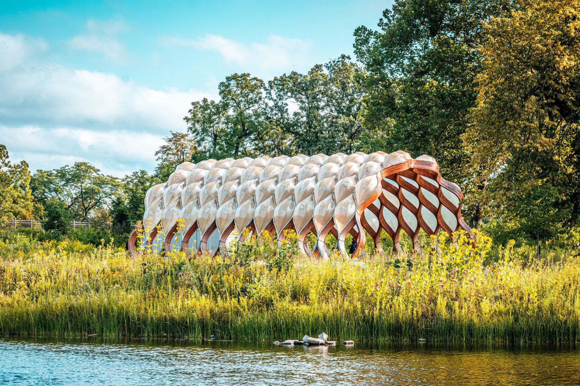 A large building is sitting on top of a grassy hill next to a body of water.