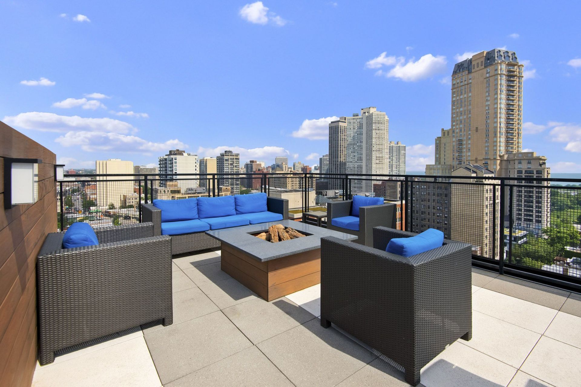 a rooftop deck with couches and a fire pit overlooking the city