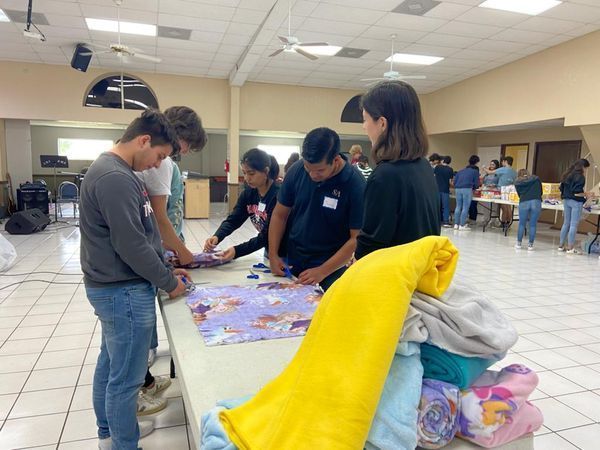 A group of people are standing around a table with blankets on it.