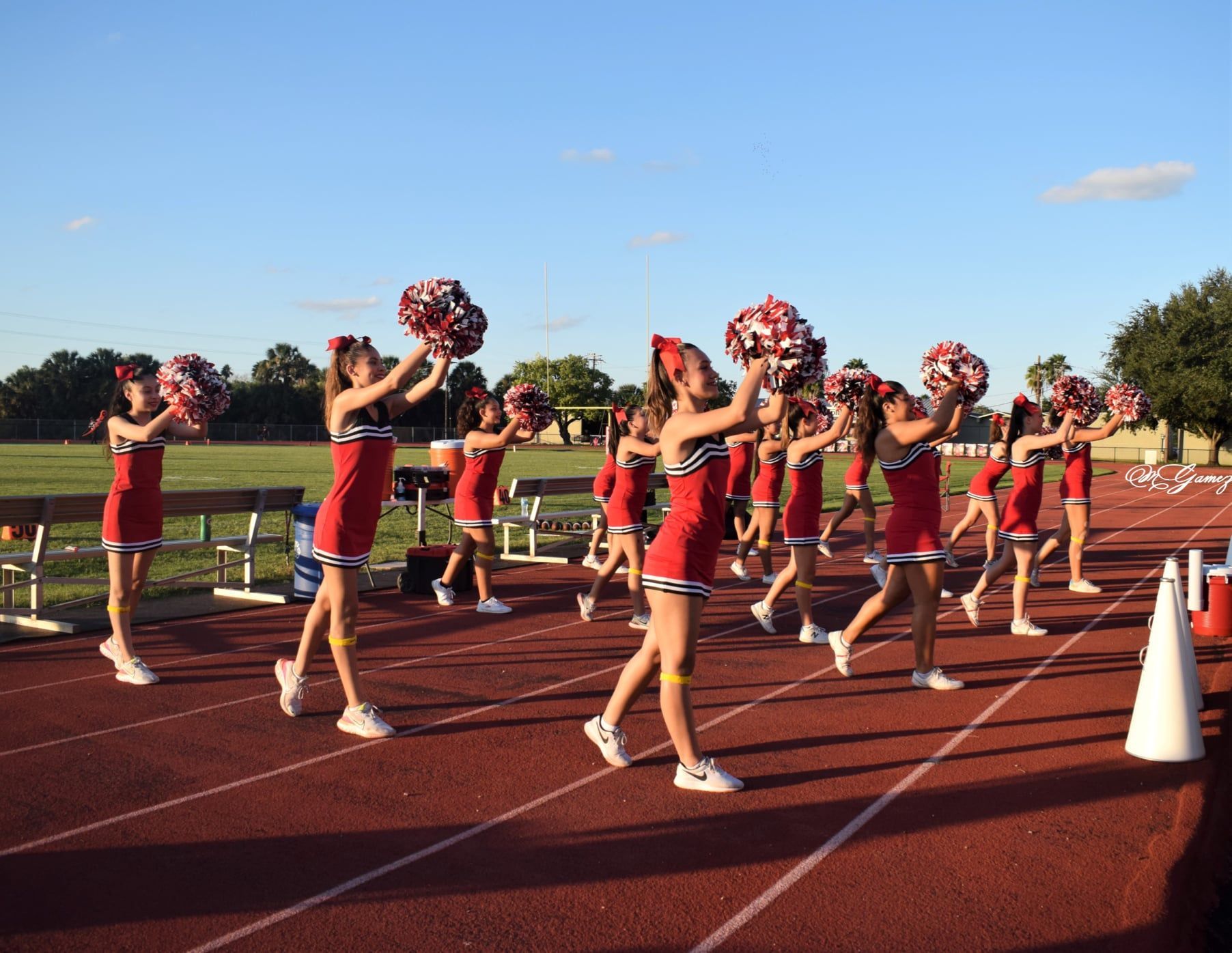 A group of cheerleaders holding pom poms on a track
