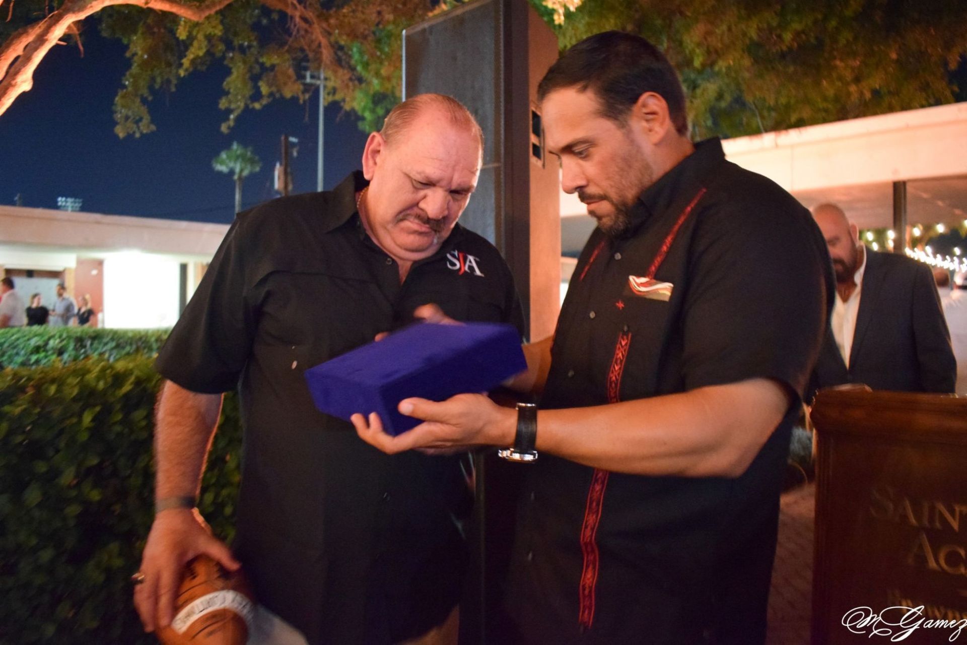 Two men in black shirts are looking at a purple box