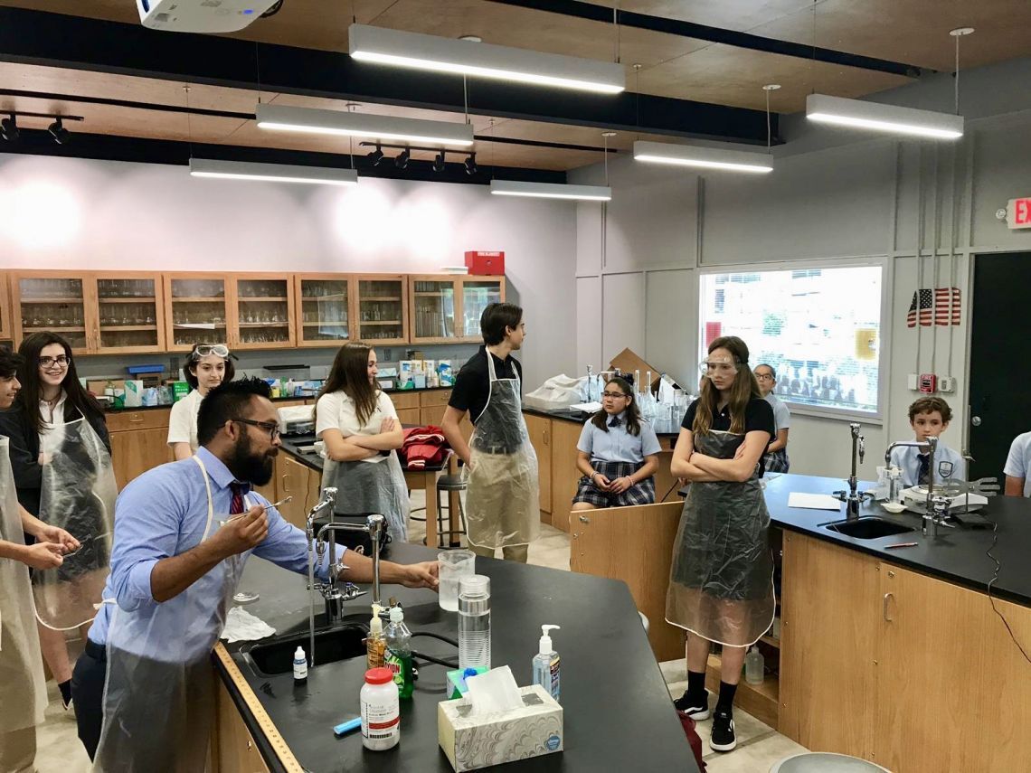 A group of people in a lab with an exit sign in the background