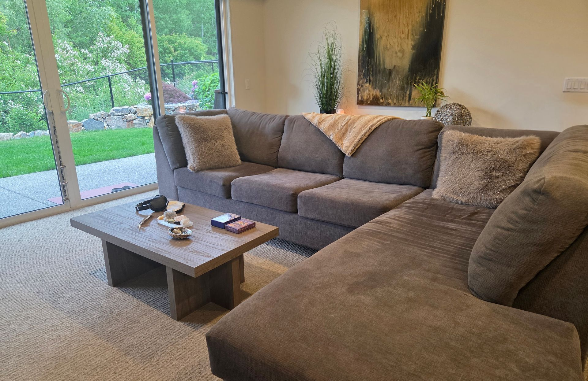 Cozy living room with a gray sectional sofa, coffee table, and large sliding glass doors to a green yard