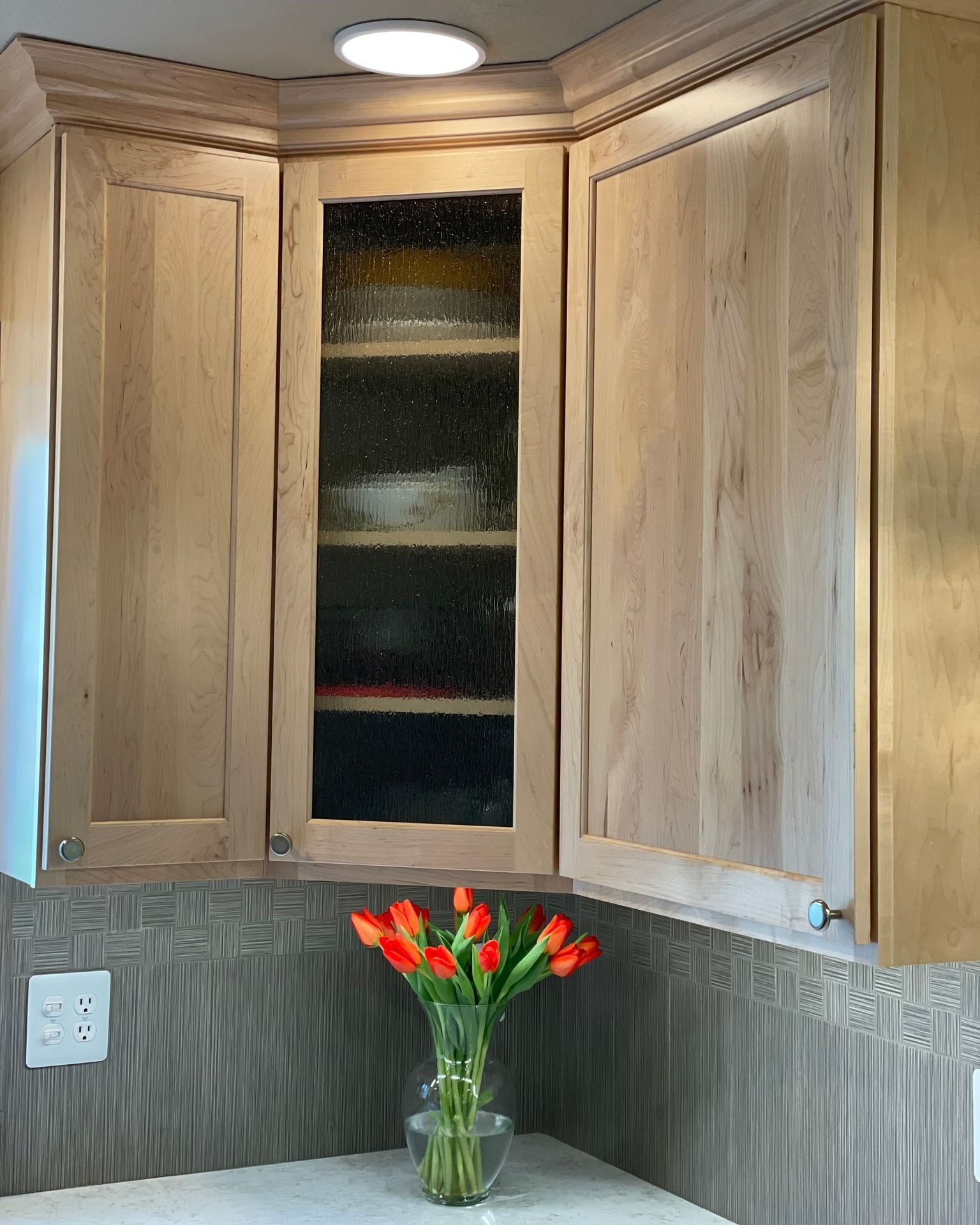 A kitchen with wooden cabinets and a vase of flowers on the counter.