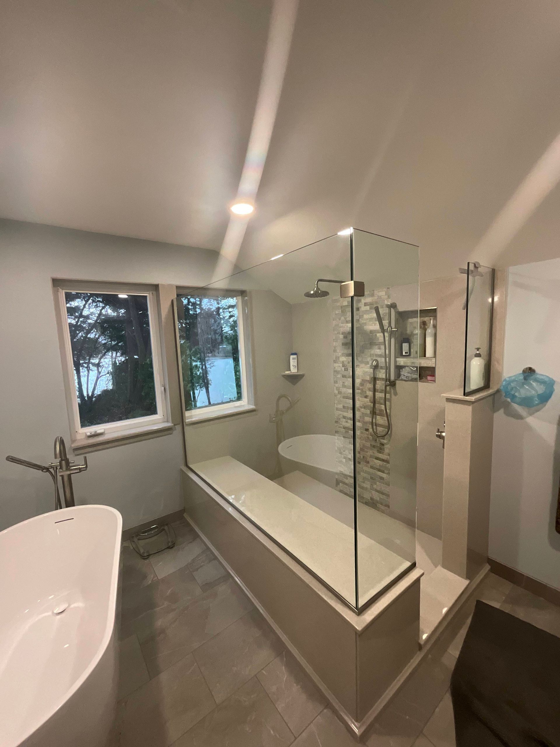 Modern bathroom with a glass-enclosed shower, built-in bench, and standalone bathtub.