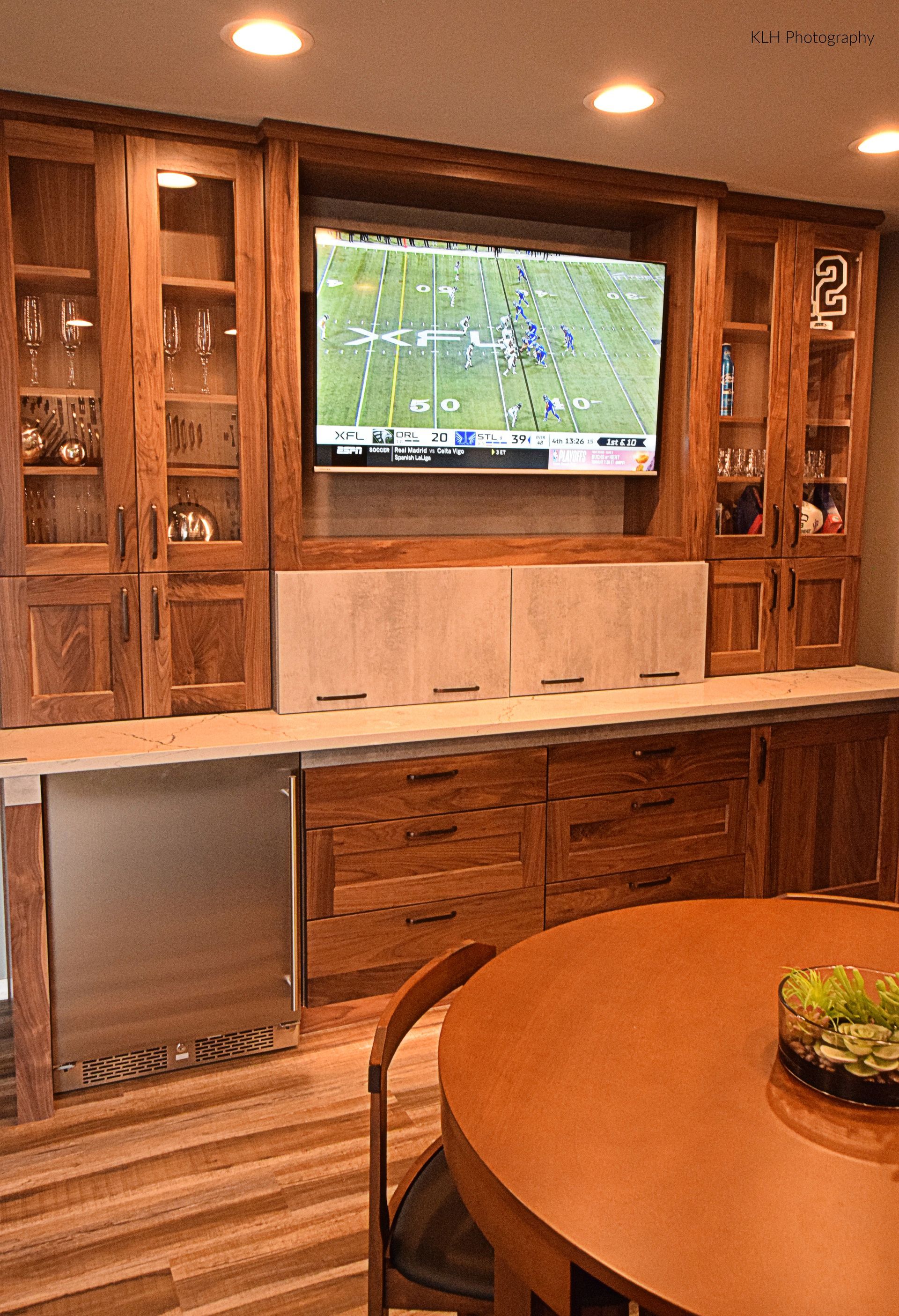 A kitchen with a round table and a flat screen tv on the wall.