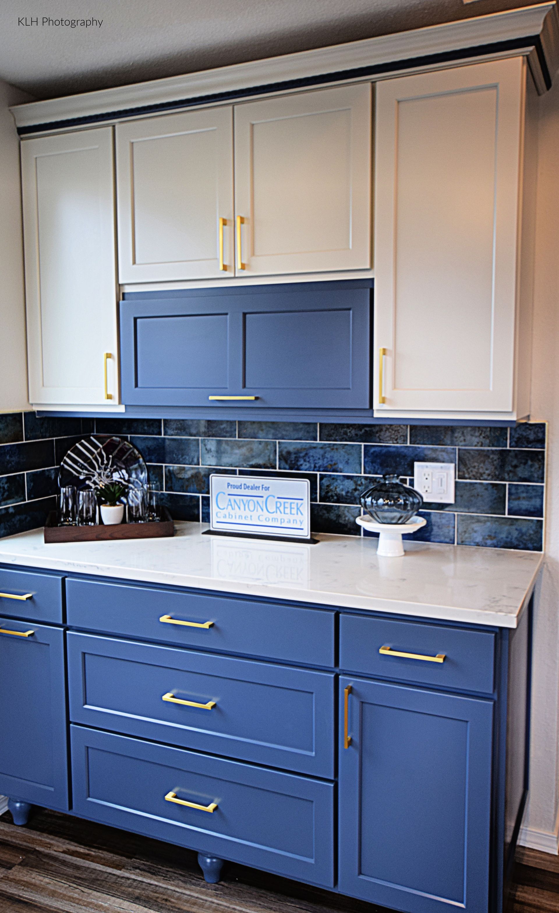 A kitchen with blue cabinets and white counter tops.