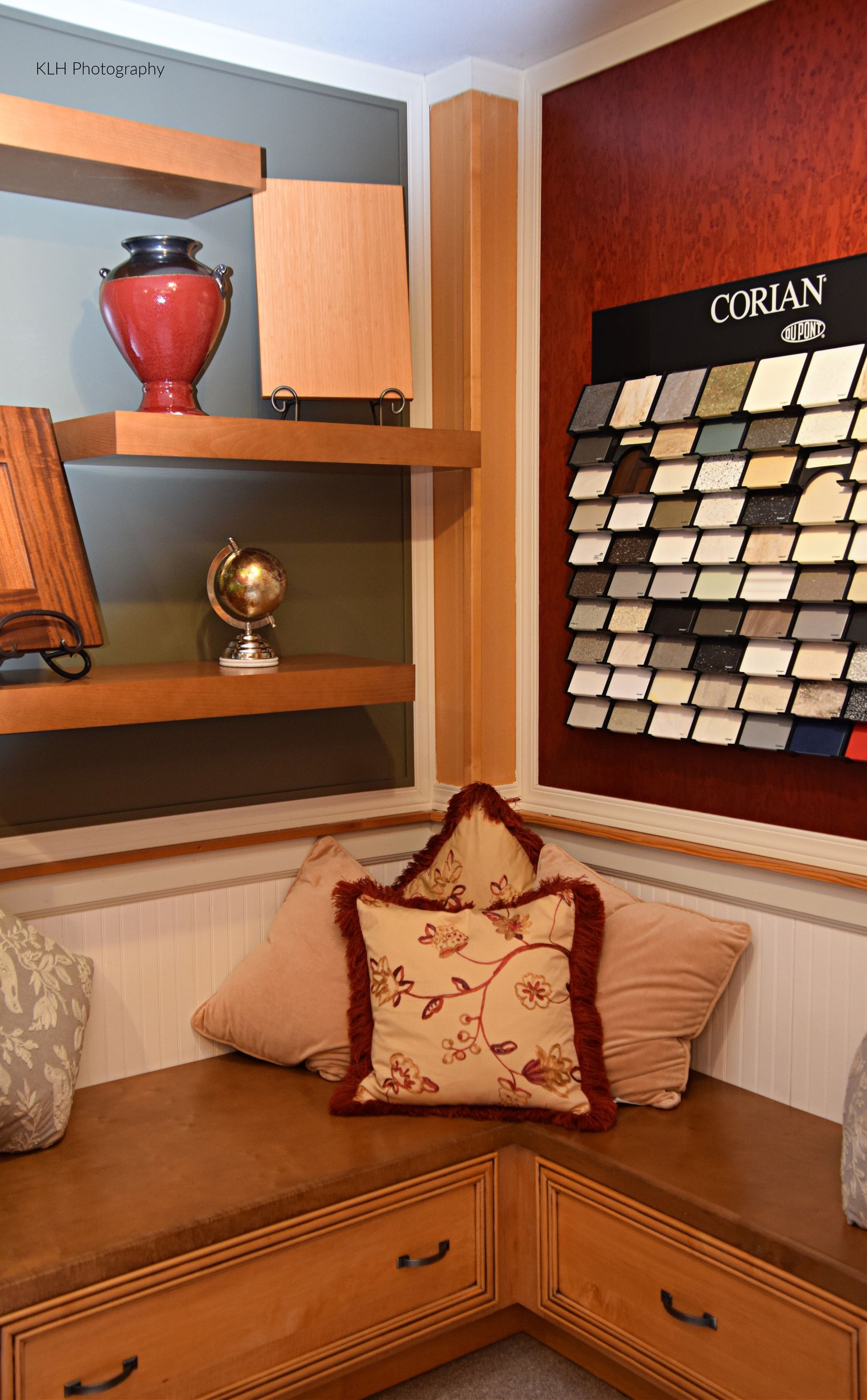 A corner of a room with a pillow on a bench.