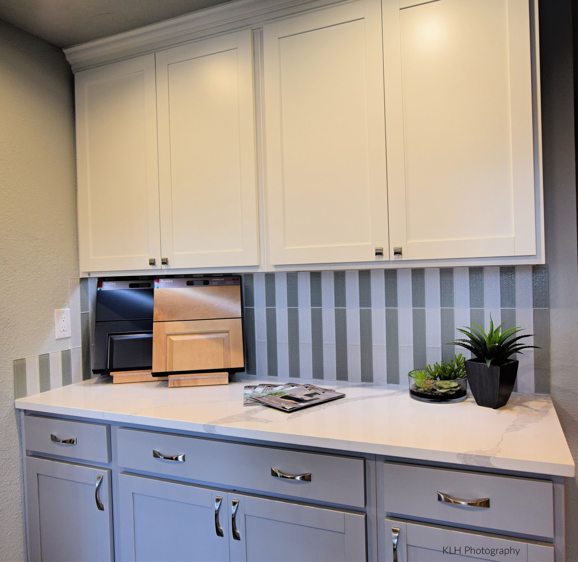 A kitchen with white cabinets and a striped wall