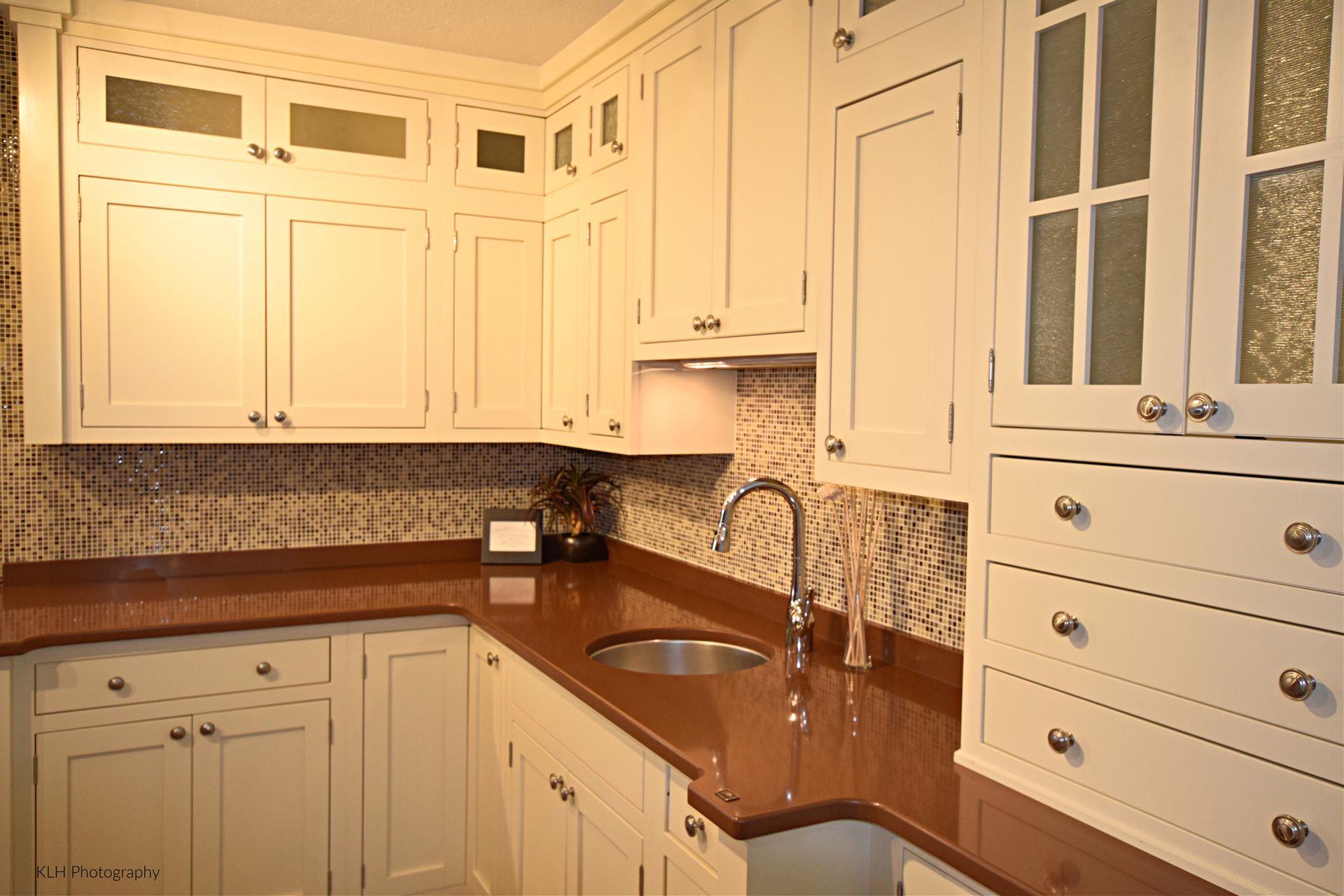 A kitchen with white cabinets and a stainless steel sink