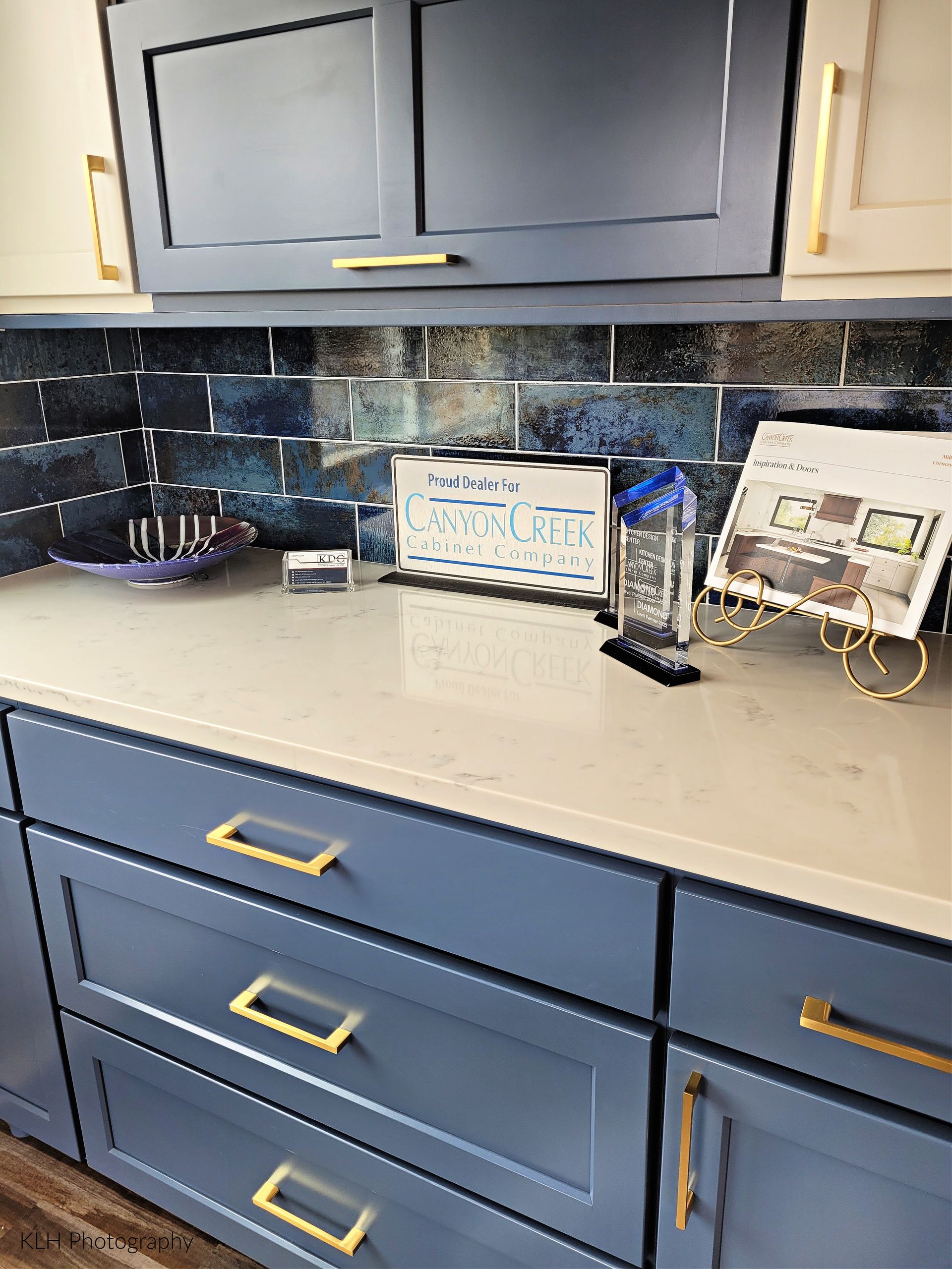 A kitchen counter with blue cabinets and gold handles.