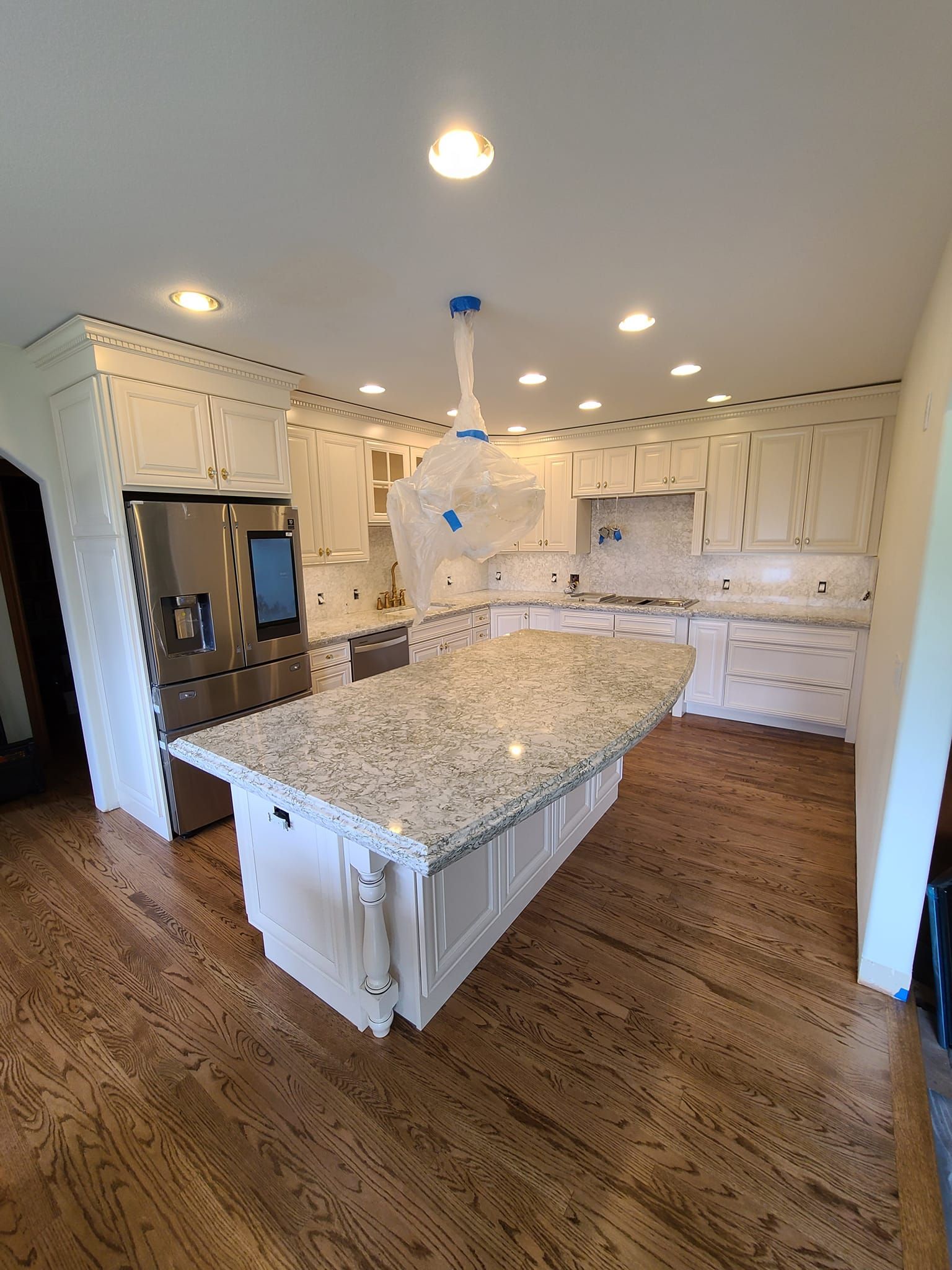 Kitchen with white cabinets, granite countertops, stainless steel appliances, and wooden floors.
