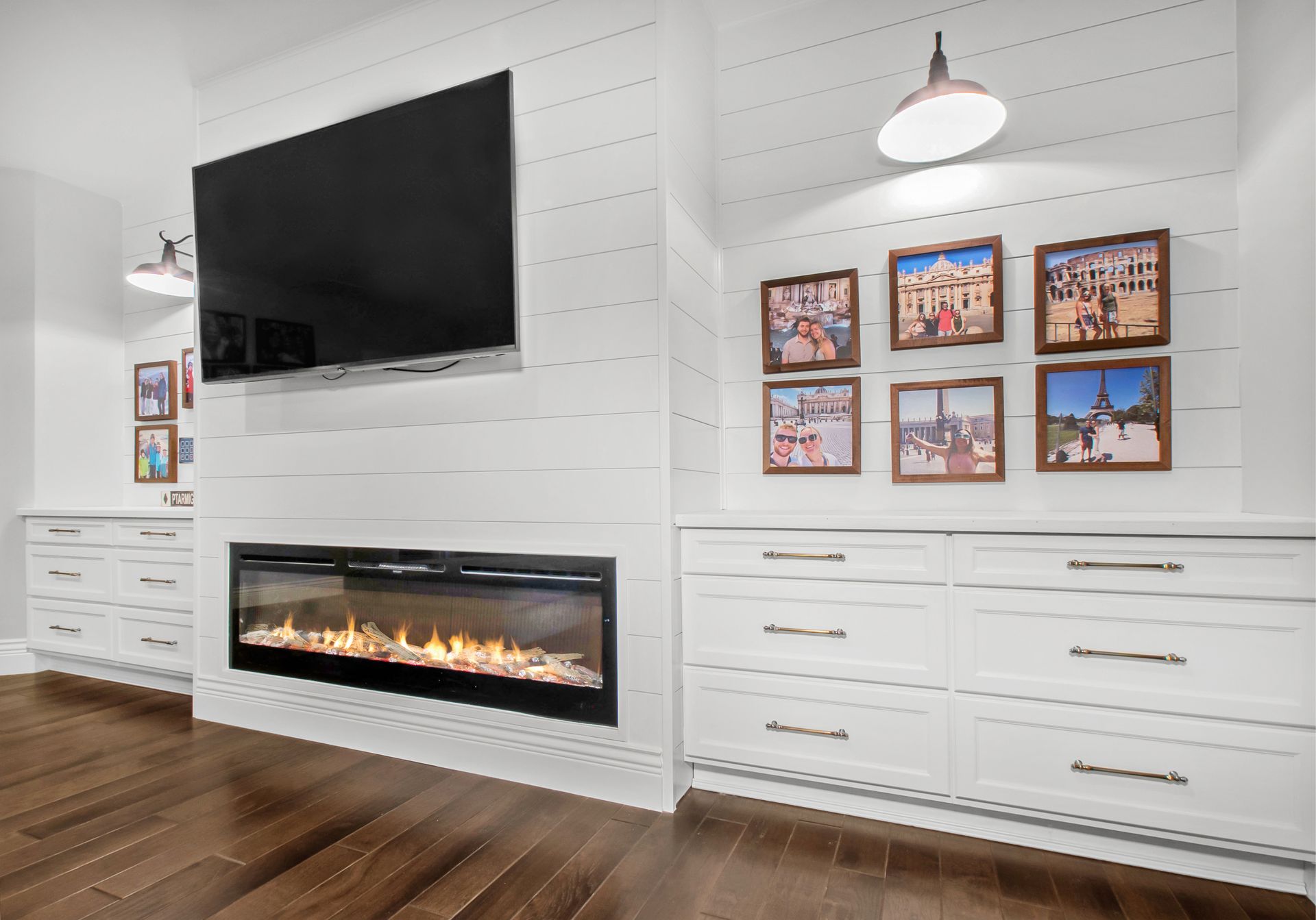 A living room with a fireplace , television , and pictures on the wall.