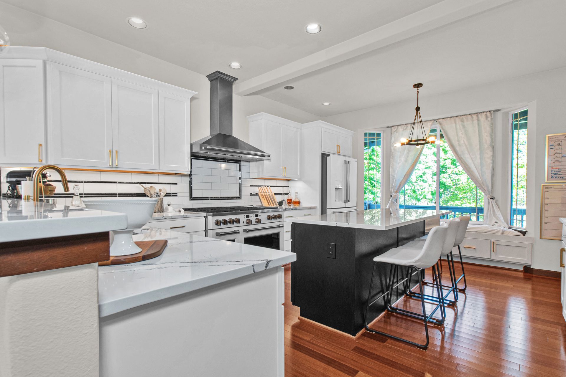 A kitchen with white cabinets , a black island , a stove and a sink.