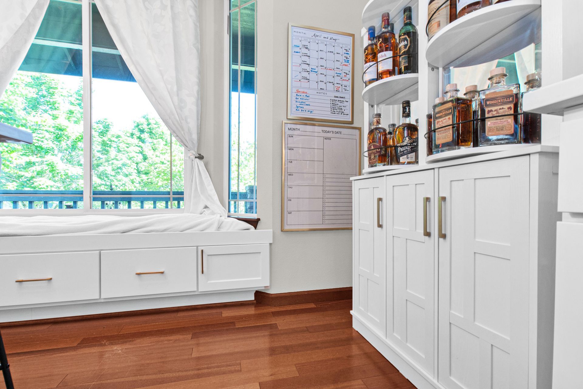 A room with white cabinets and shelves filled with bottles of alcohol.