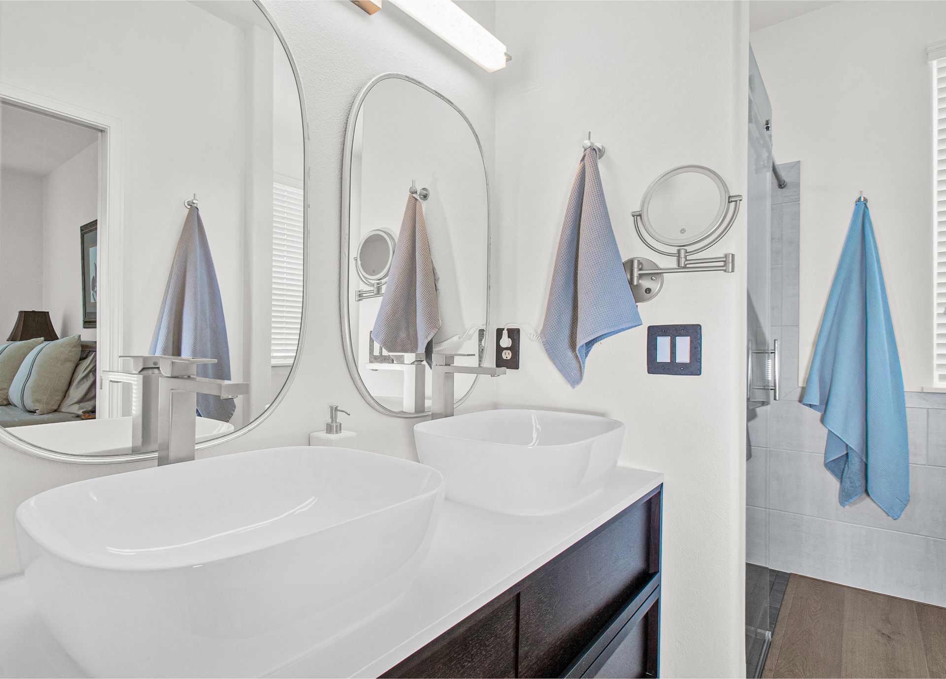 A bathroom with two sinks , two mirrors , and towels hanging on the wall.