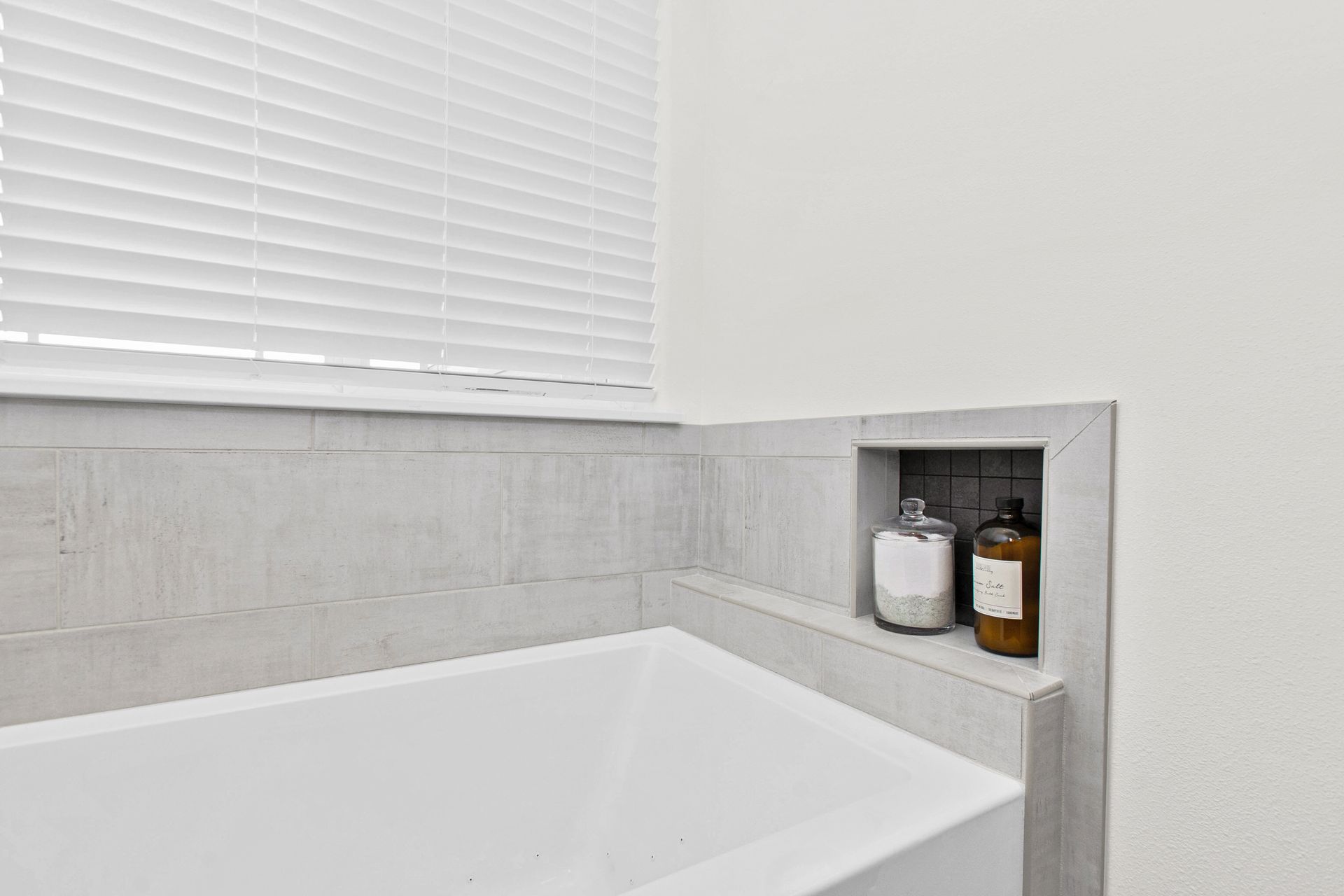 A bathroom with a bathtub and a window with blinds.