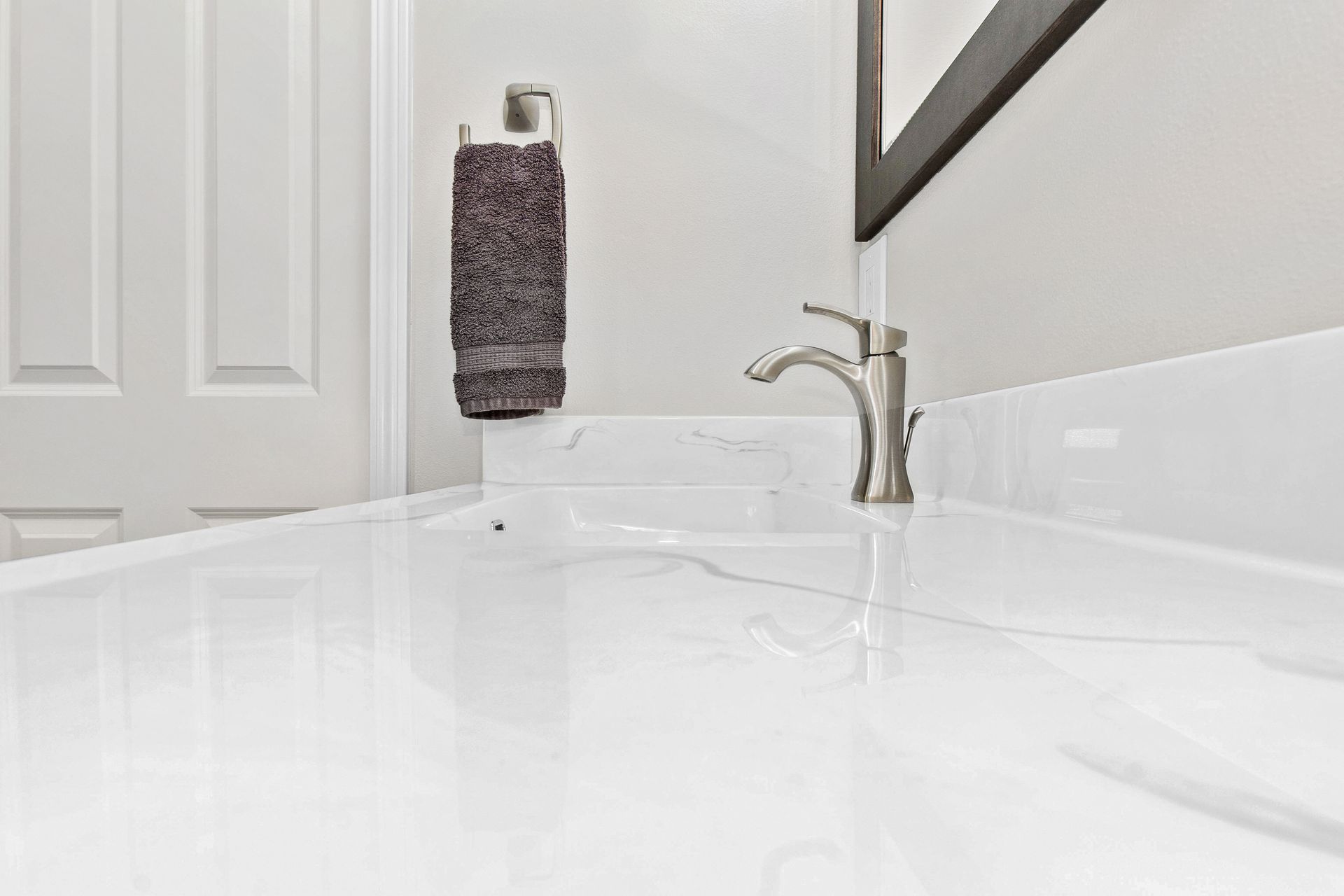 A bathroom sink with a faucet and a towel hanging on the wall.