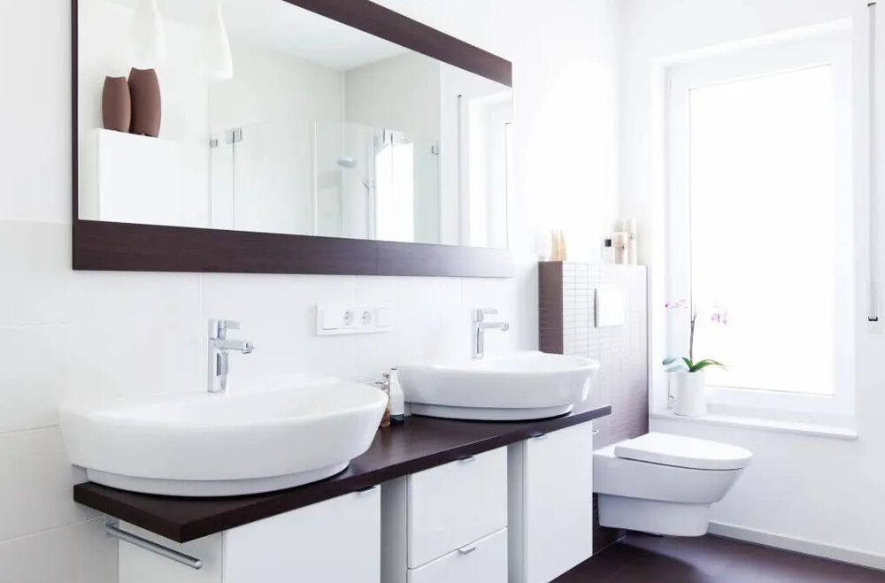 A bathroom with two sinks , a toilet and a large mirror.