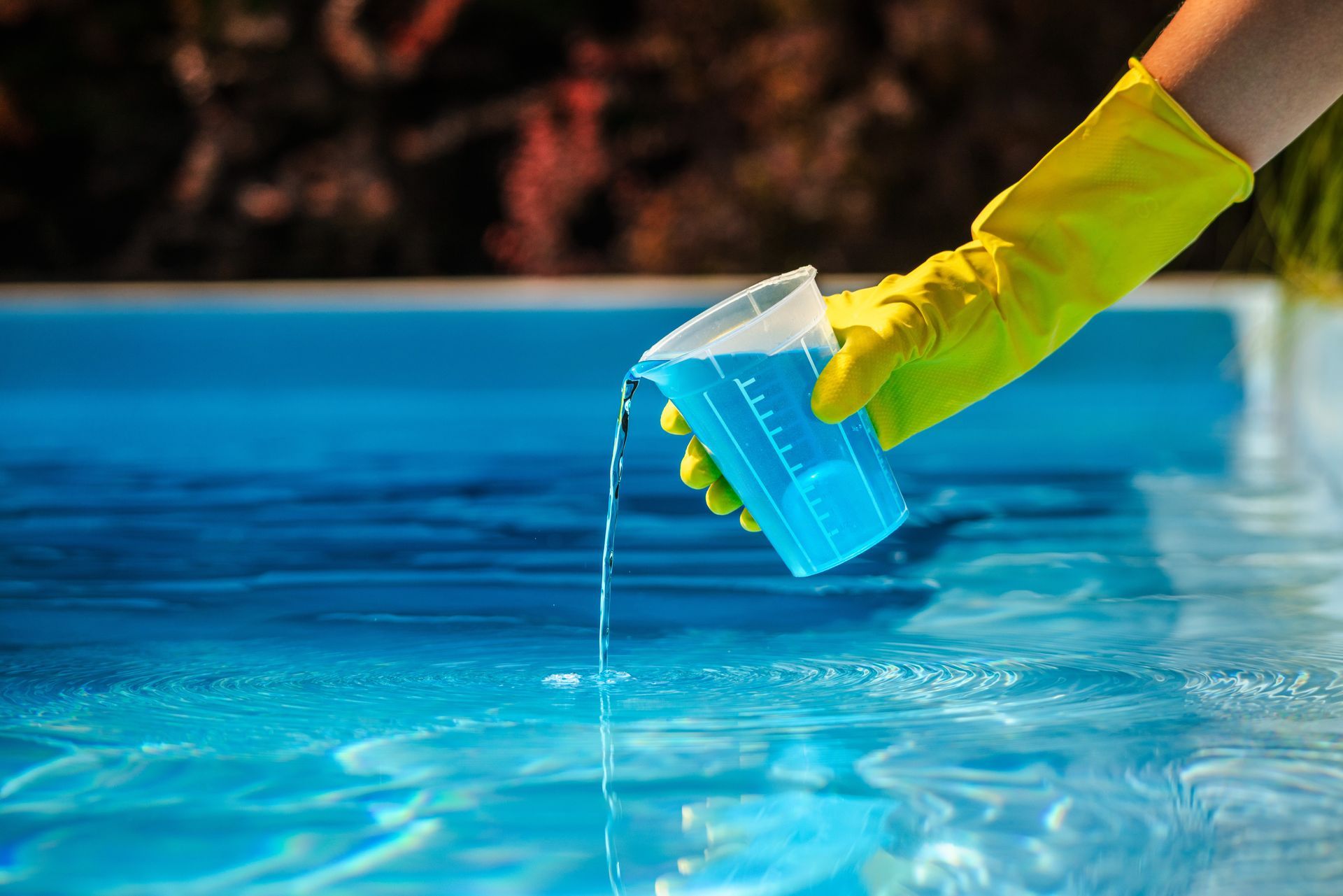 A man is pouring a chemical in a pool. A man is pouring a chemical in a pool.