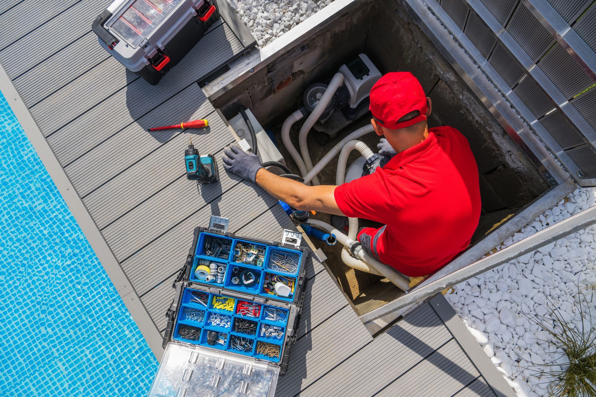 A man is providing maintenance to the heating system of a pool.