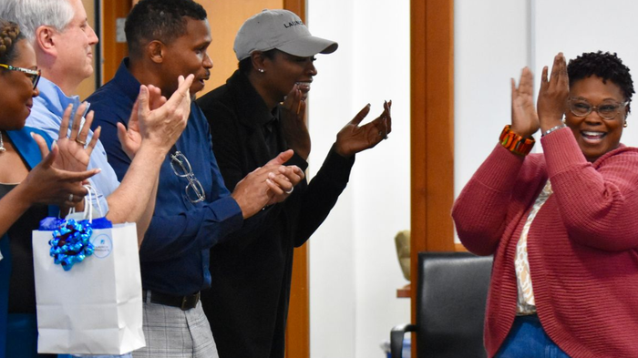 Woman in sweater clapping as team cheers are own at graduation