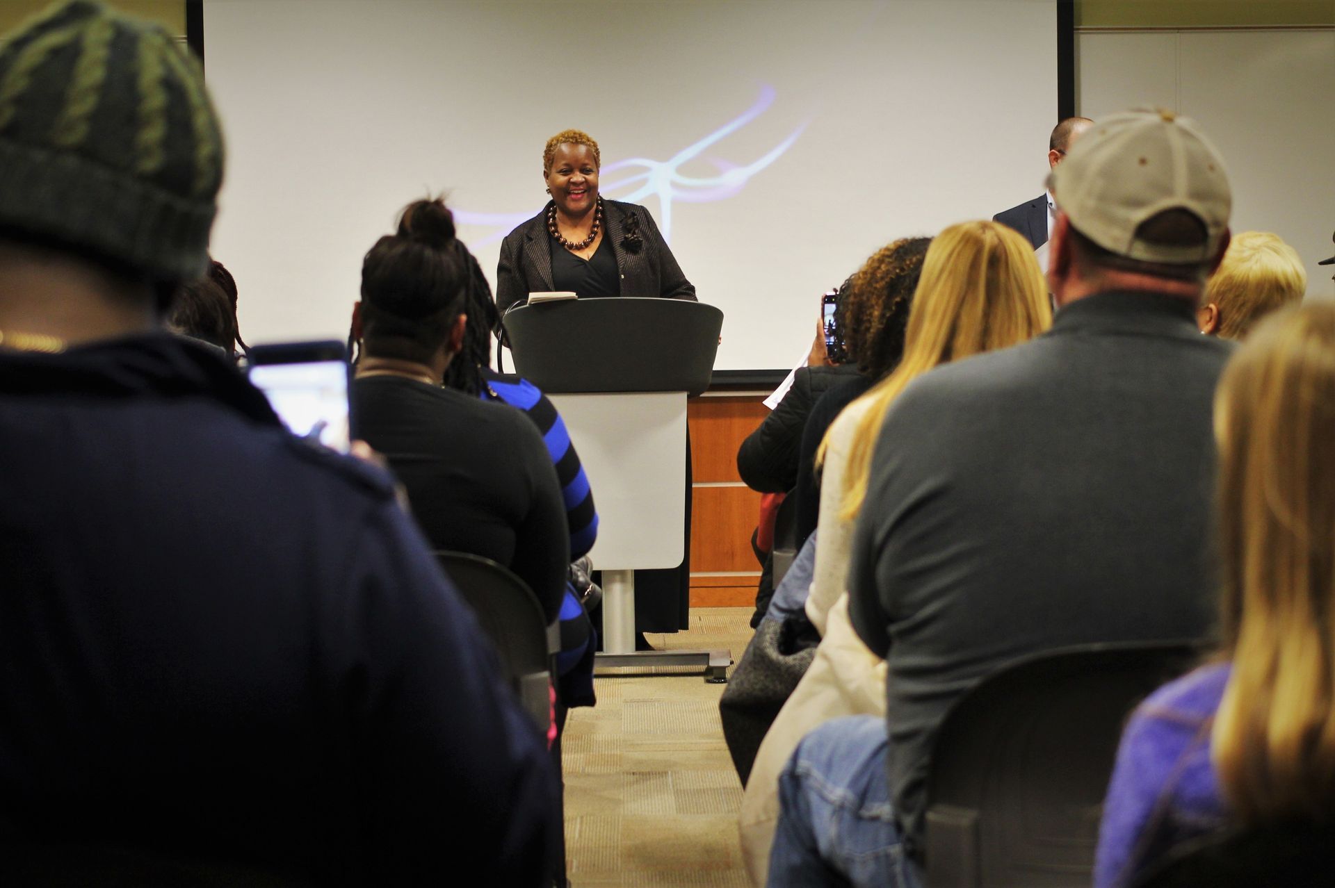 Speaker at podium addressing an audience in a small classroom or conference room