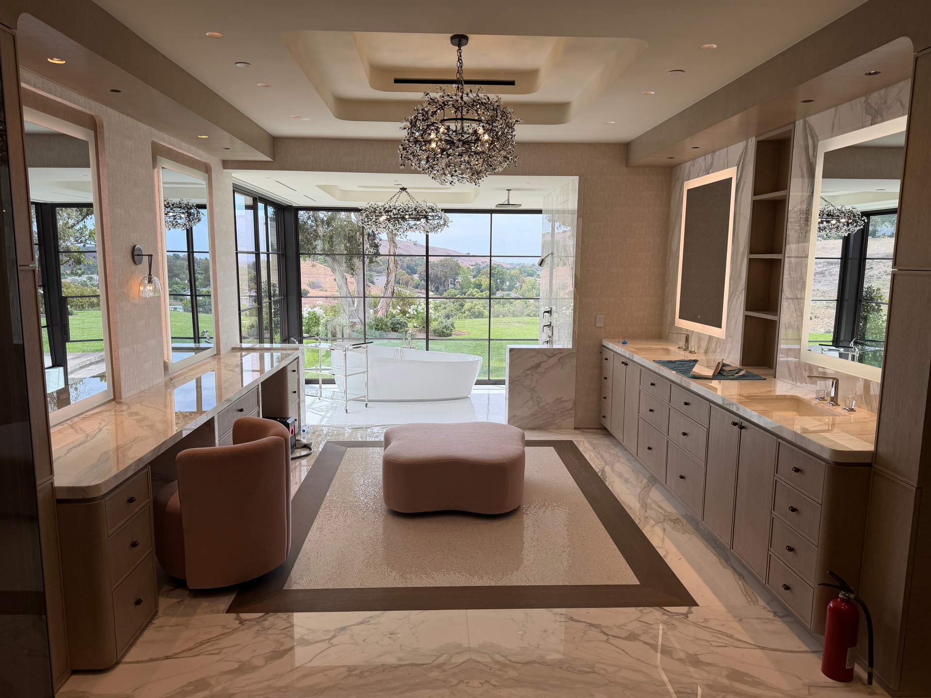 Bright bathroom vanity with twin round mirrors, white cabinets, and a window between two sinks
