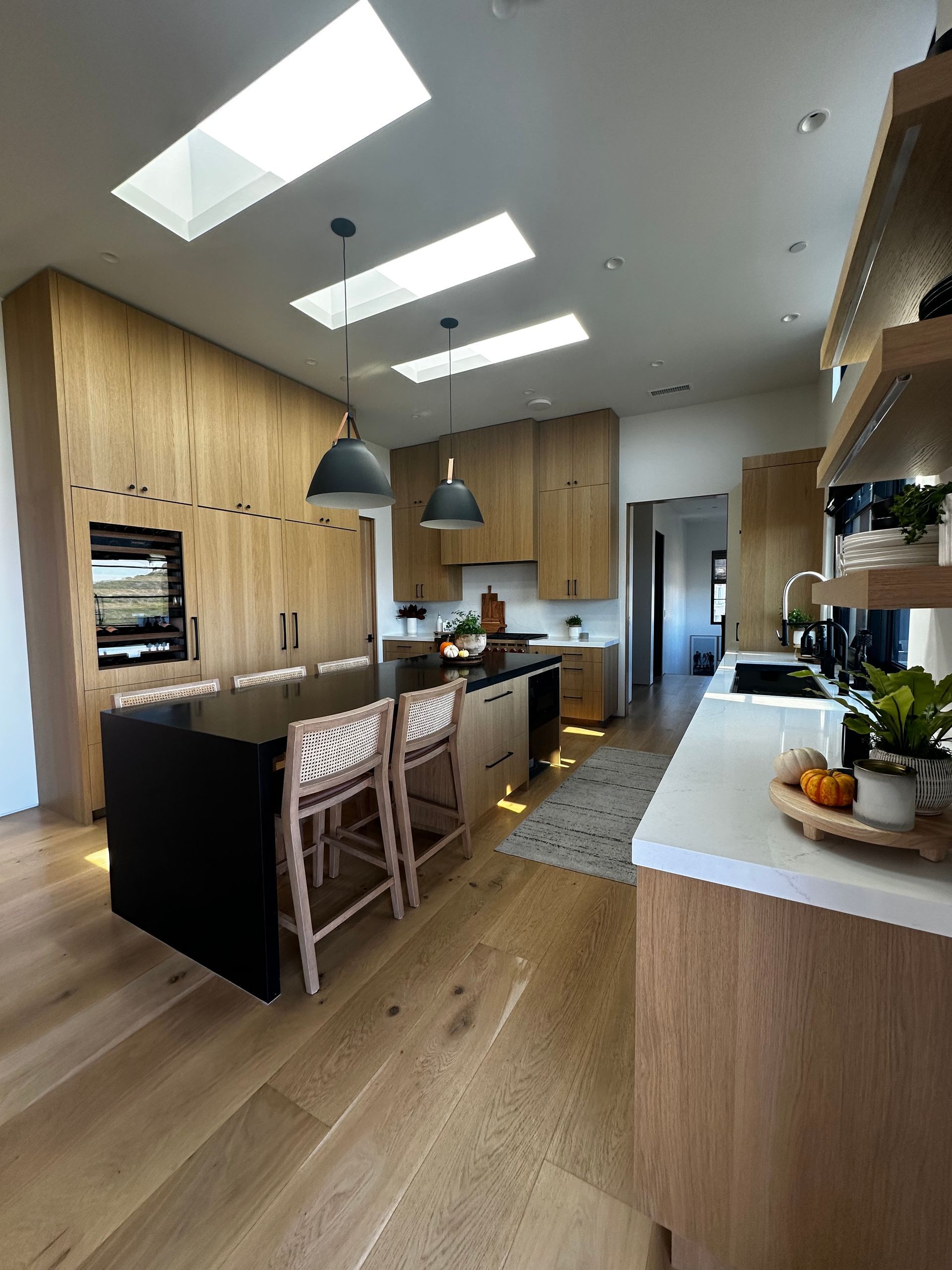Modern kitchen with blue cabinets, wood floor, stainless appliances, and a white island countertop