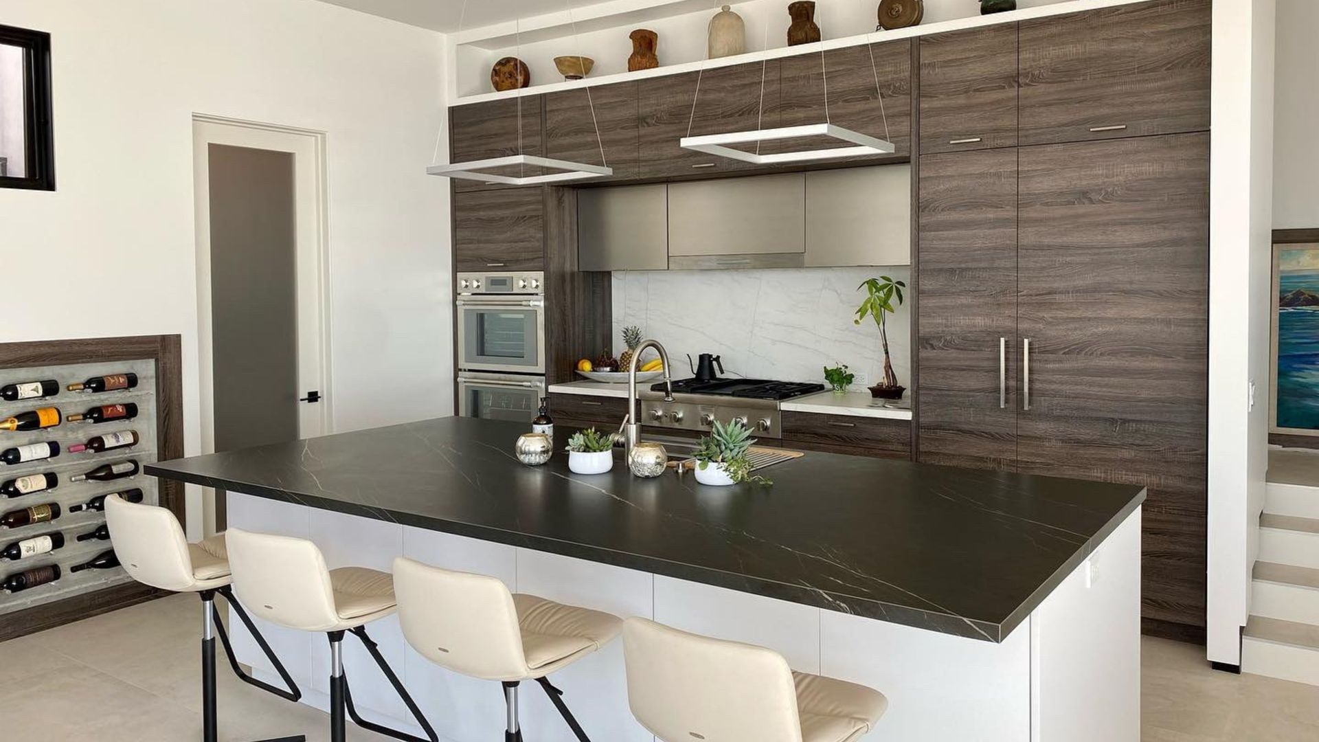 Modern kitchen with large island, bar stools, wood cabinetry, and stainless steel appliances