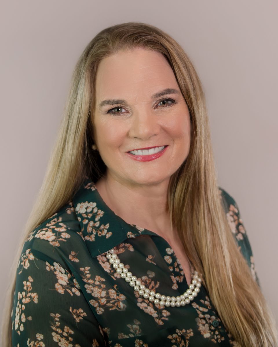 Lori Parkins in a dark floral top against a light background