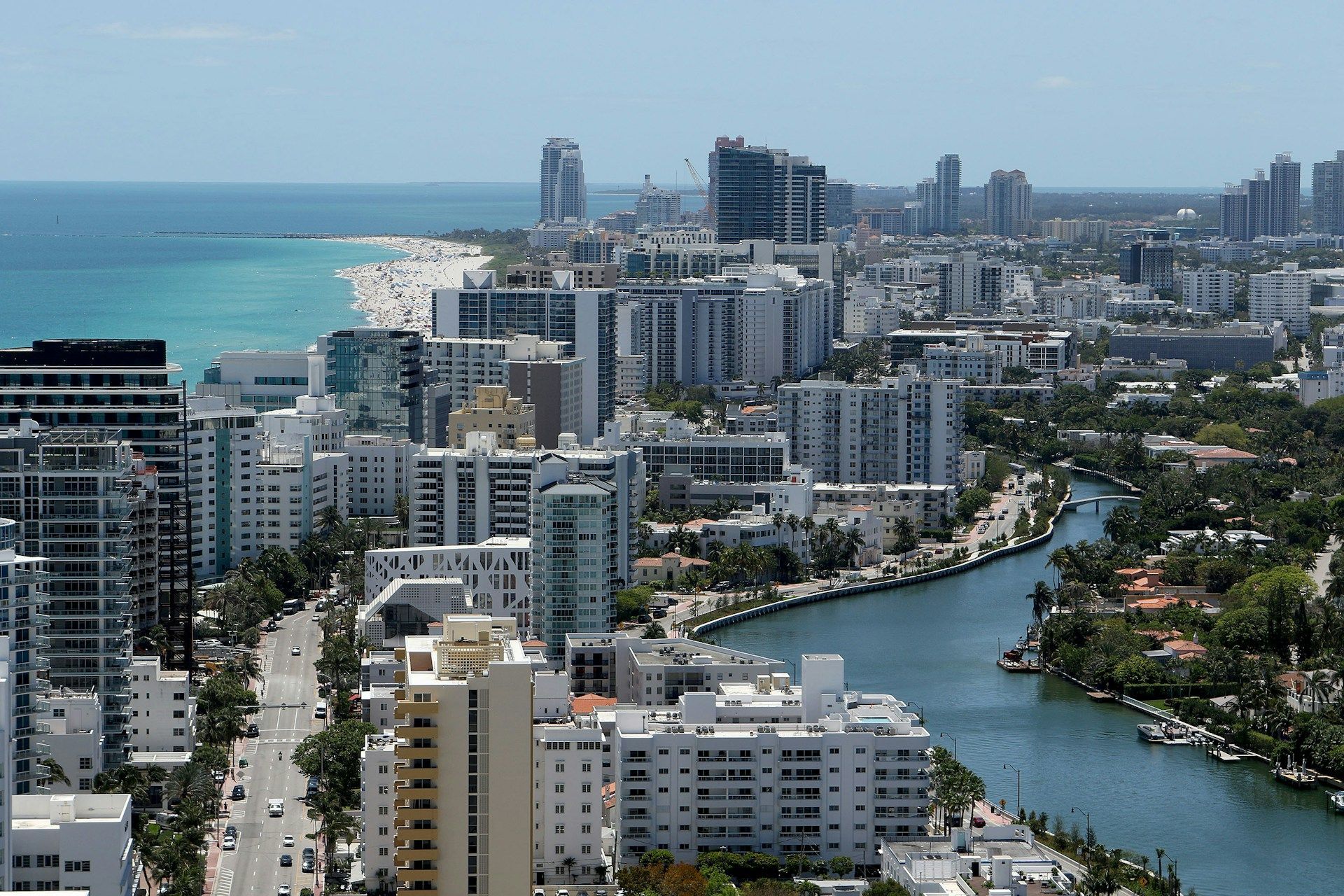 Coastal city skyline with high-rise buildings beside a turquoise river and the ocean in the distance