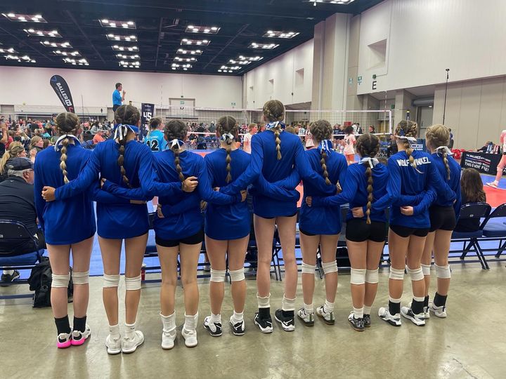 A group of volleyball players are standing in a row with their arms around each other.
