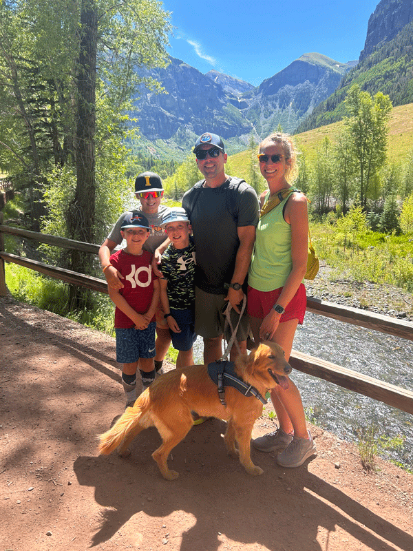 A family is standing next to a dog on a trail.