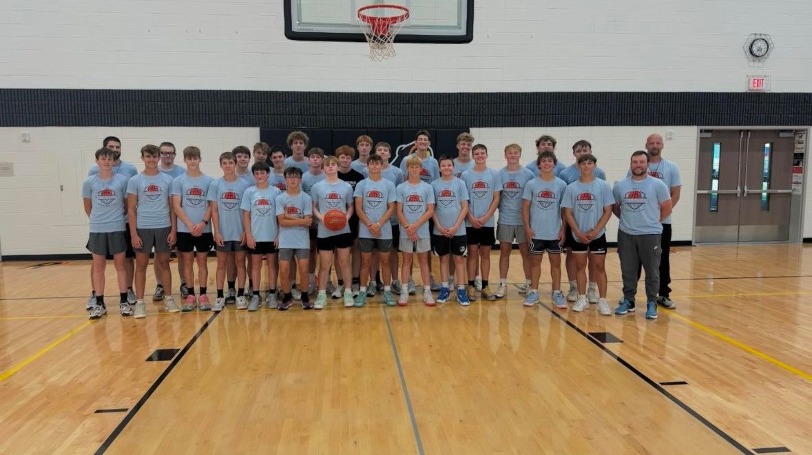 A group of people are posing for a picture in a gym.