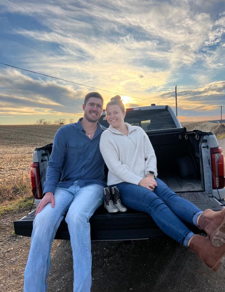 A man and a woman are sitting in the back of a truck.