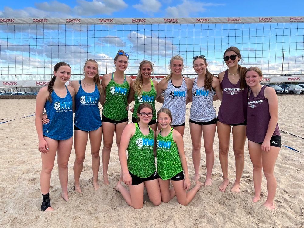 A group of young women are posing for a picture on a beach.